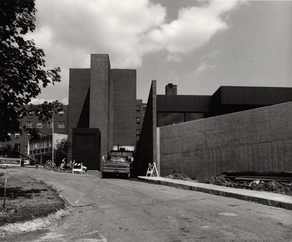 A black-and-white photo of a truck and a building