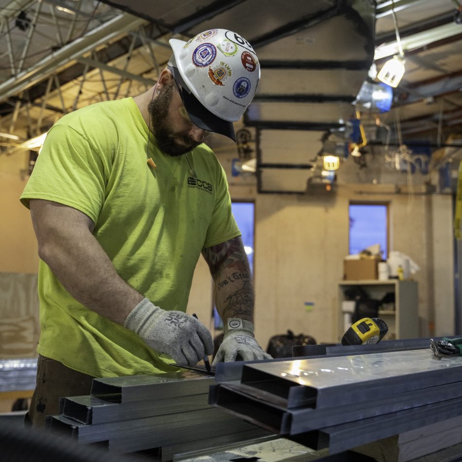 A worker measuring and cutting metal