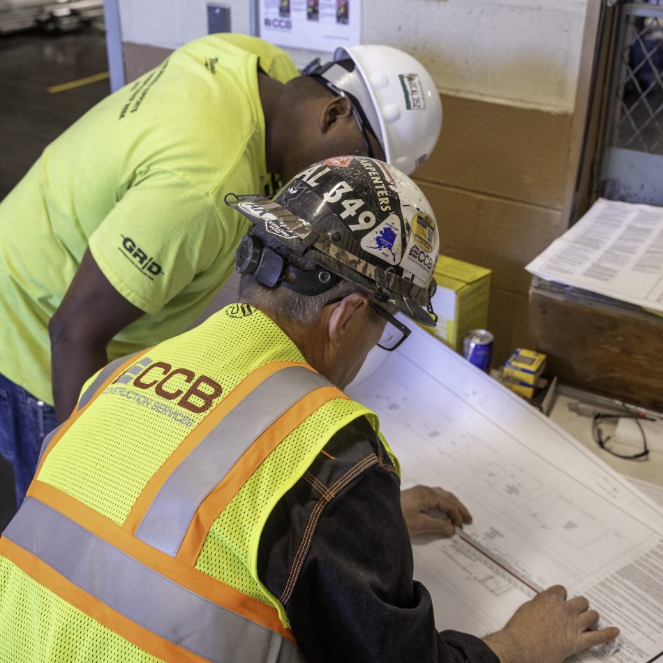 Two workers reviewing blueprints