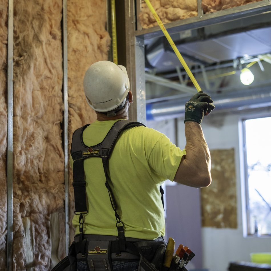 A worker measuring insulation